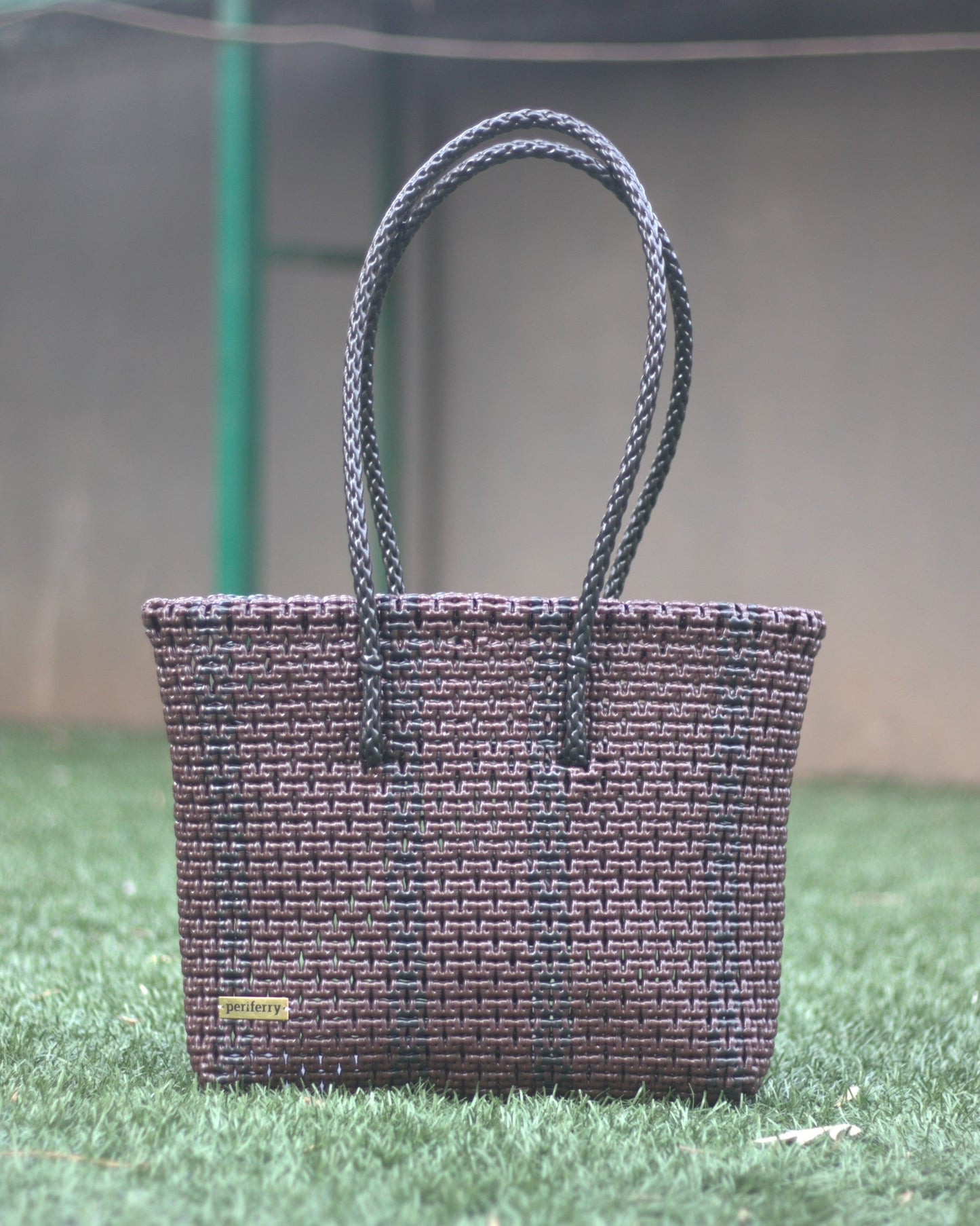 Brown and Black knitted handbag on grass with a blurred background