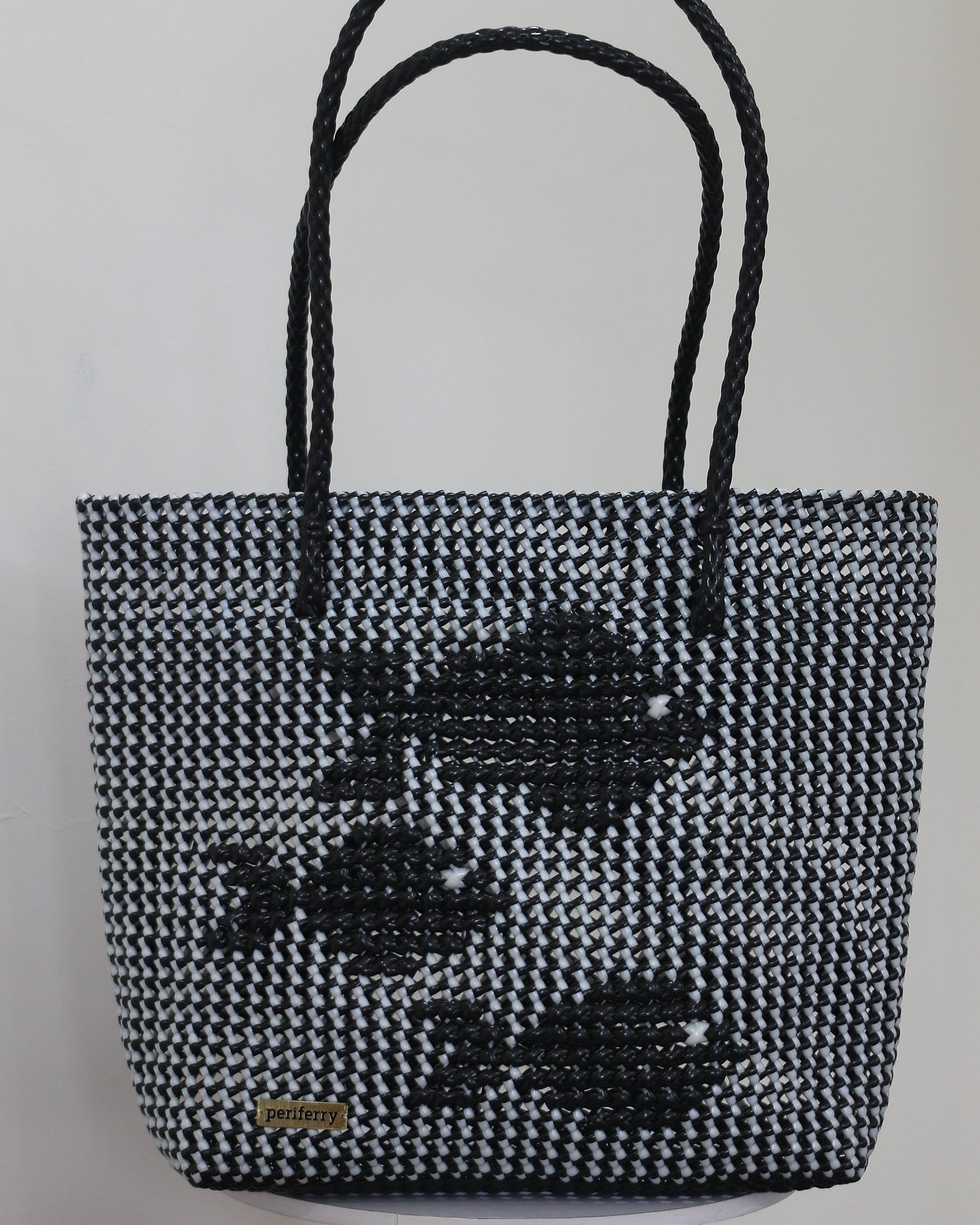 Black and white knitted handbag with knitted fish patterns on a light gray background