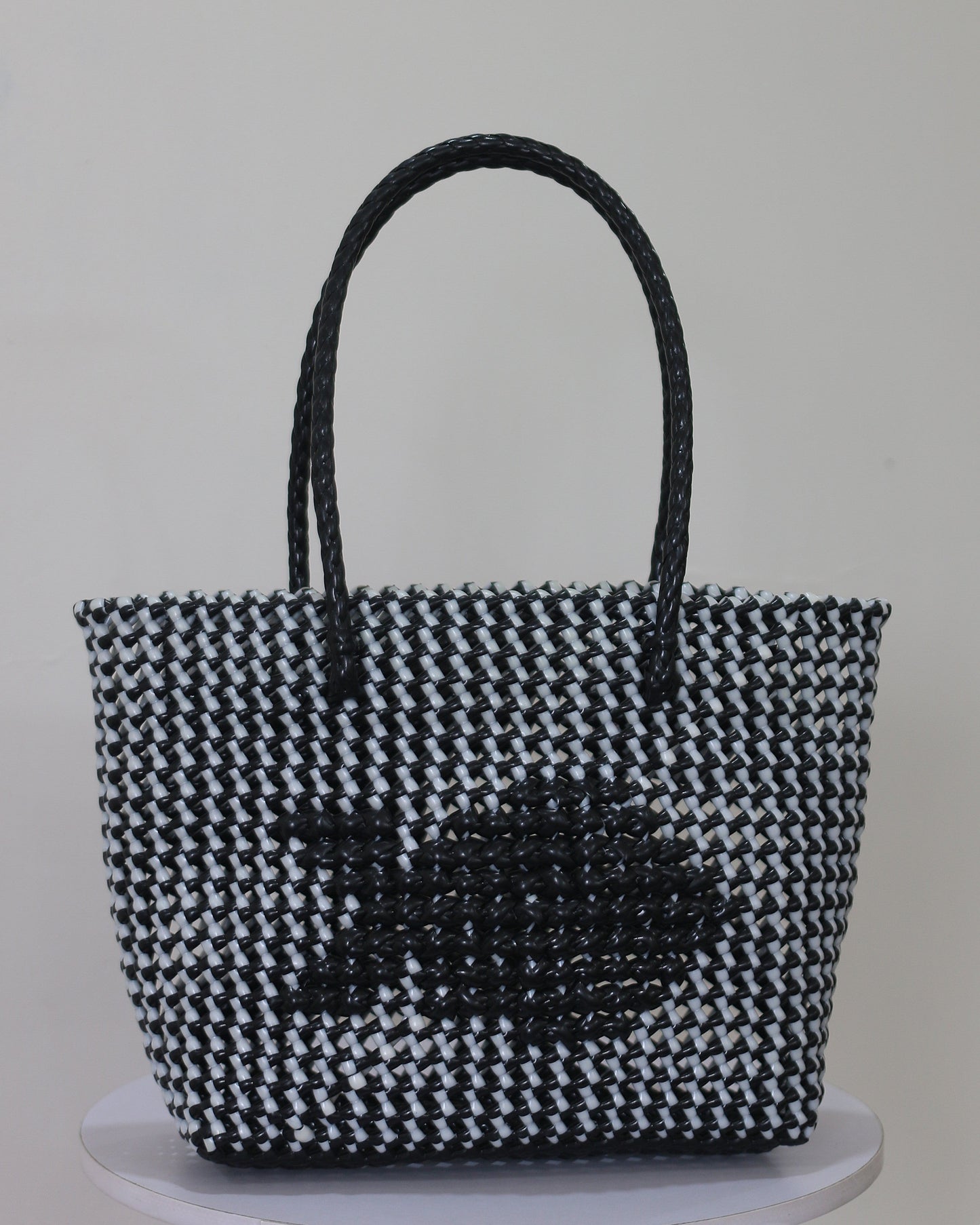 Black and white knitted handbag with knitted fish pattern on a gray background