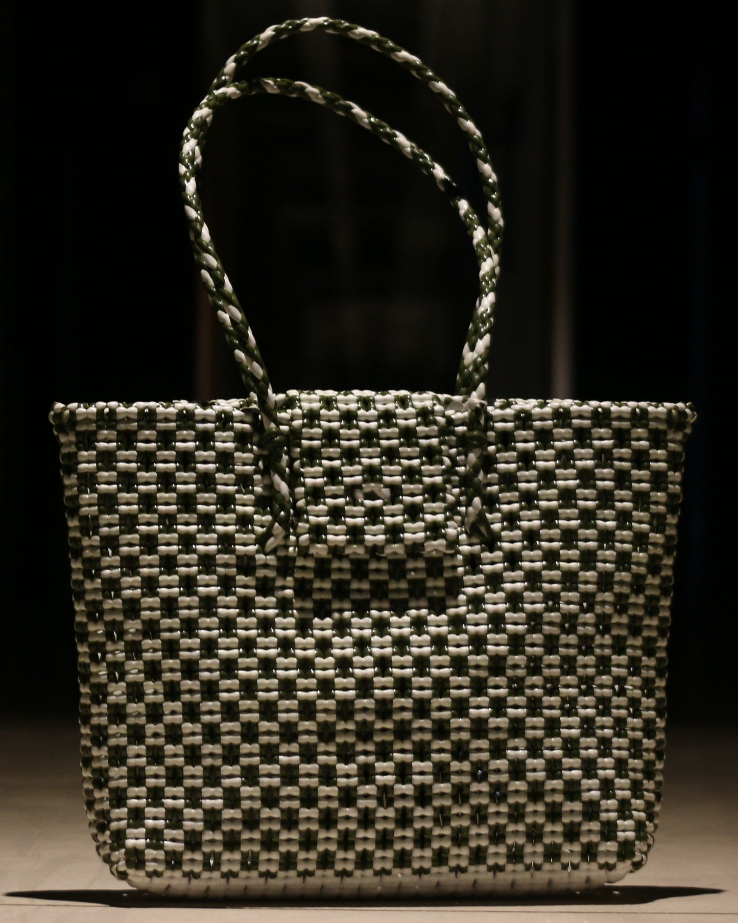 Green and White knitted handbag on a wooden surface with a dark background