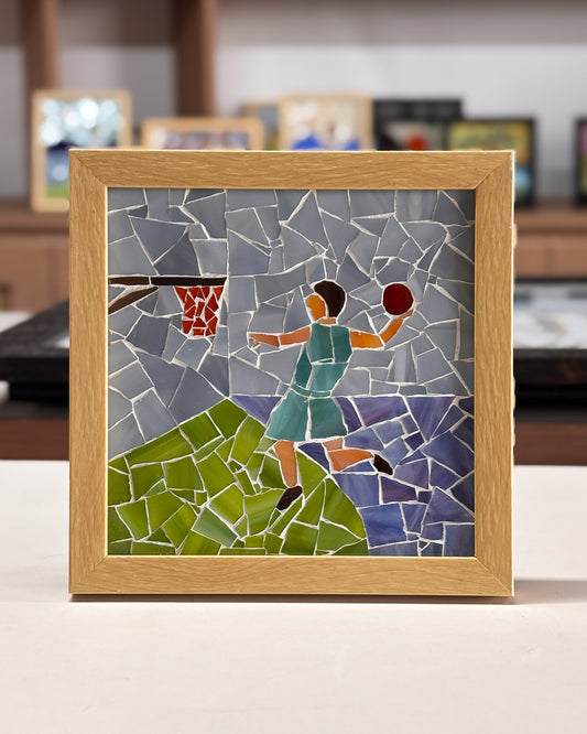 Mosaic artwork of a person playing basketball in a wooden frame.