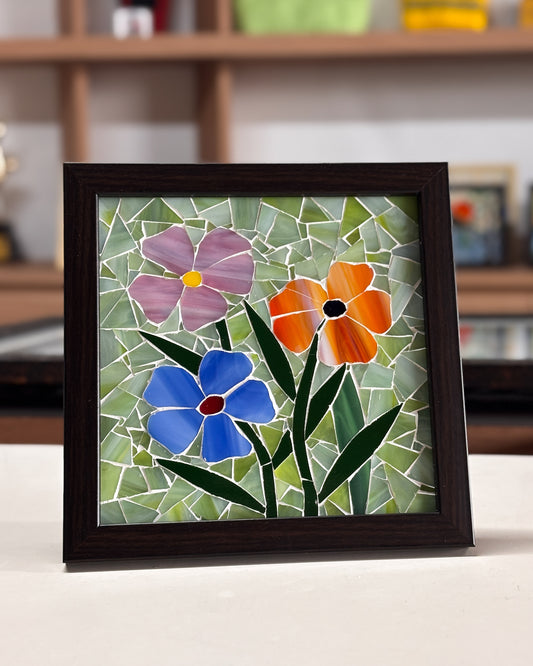 Framed mosaic artwork of flowers on a table with a blurred background