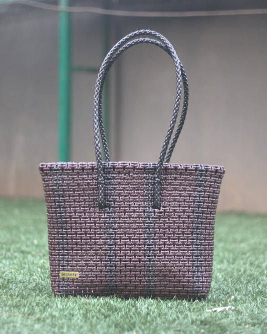 Brown and Black knitted handbag on grass with a blurred background