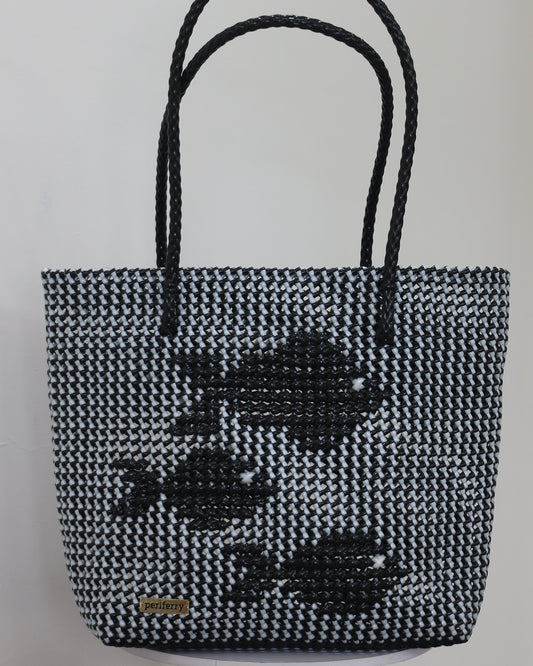 Black and white knitted handbag with knitted fish patterns on a light gray background