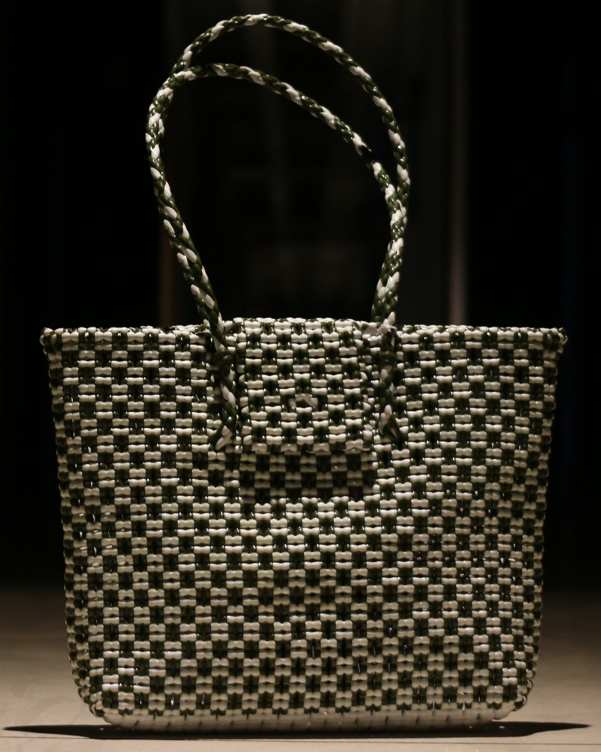 Green and White knitted handbag on a wooden surface with a dark background