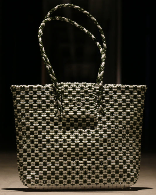 Green and White knitted handbag on a wooden surface with a dark background