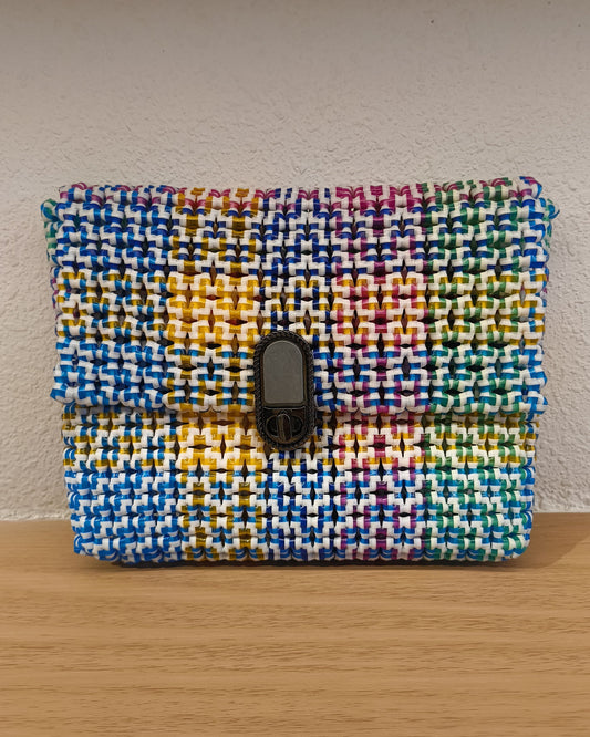 Rainbow colored knitted pouch with a metallic buckle on a wooden surface.
