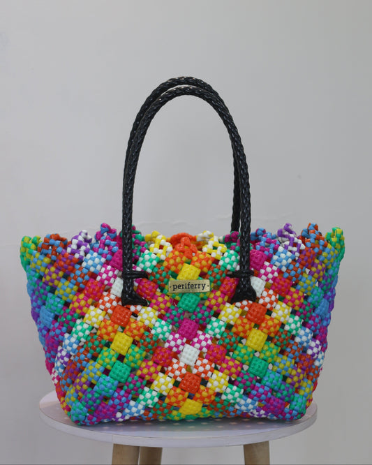 Colorful knitted handbag on a white stool against a gray background